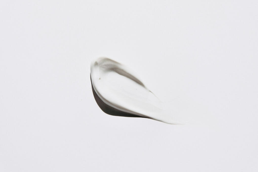 A single smear of white cream on a plain white background